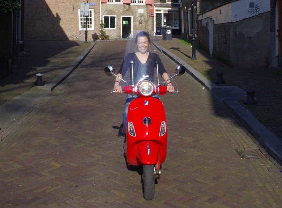 driving through town on a red vespa lx