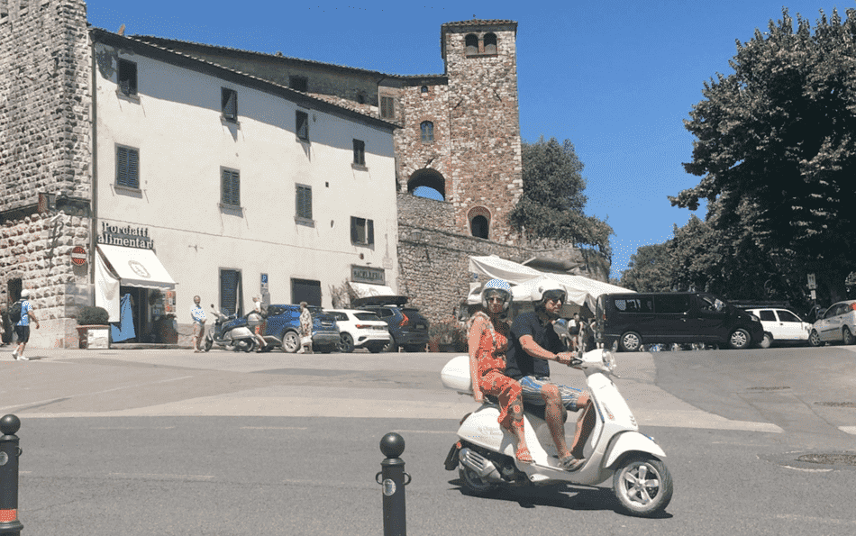 couple driving on a vespa rental