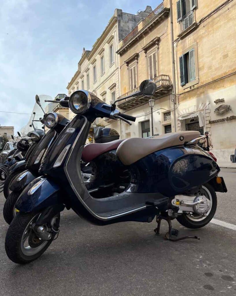 dark blue vespa primavera parked in city center